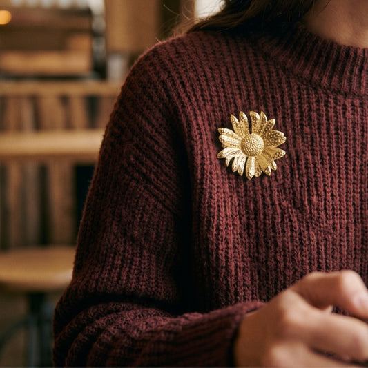 Bloem broche goud op een bordeaux trui