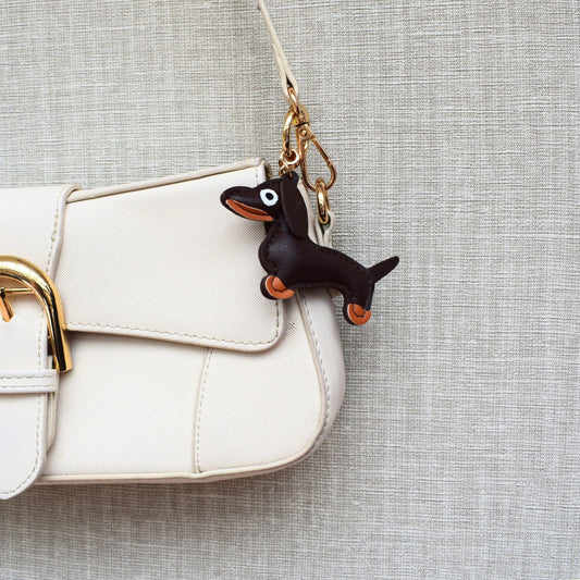 Hond van stof bag charm aan witte tas