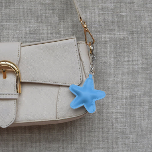 Ster van stof bag charm lichtblauw aan witte tas