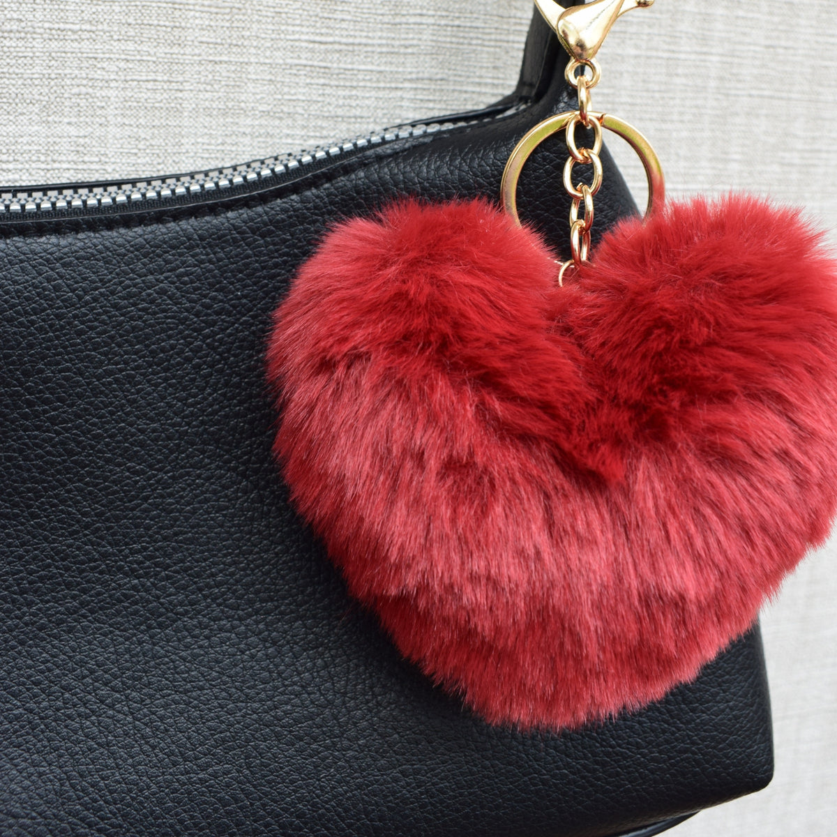 Fluffy hart bag charm rood aan zwarte tas