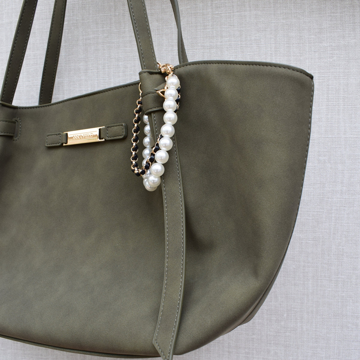 Parels bag charm zwart gedragen aan groene tas