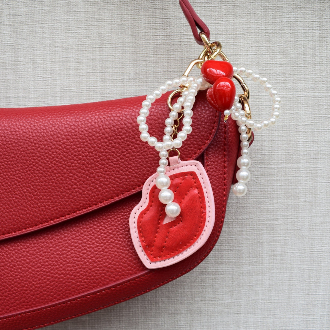 Bag charm met parels en rode lippen aan een rode tas