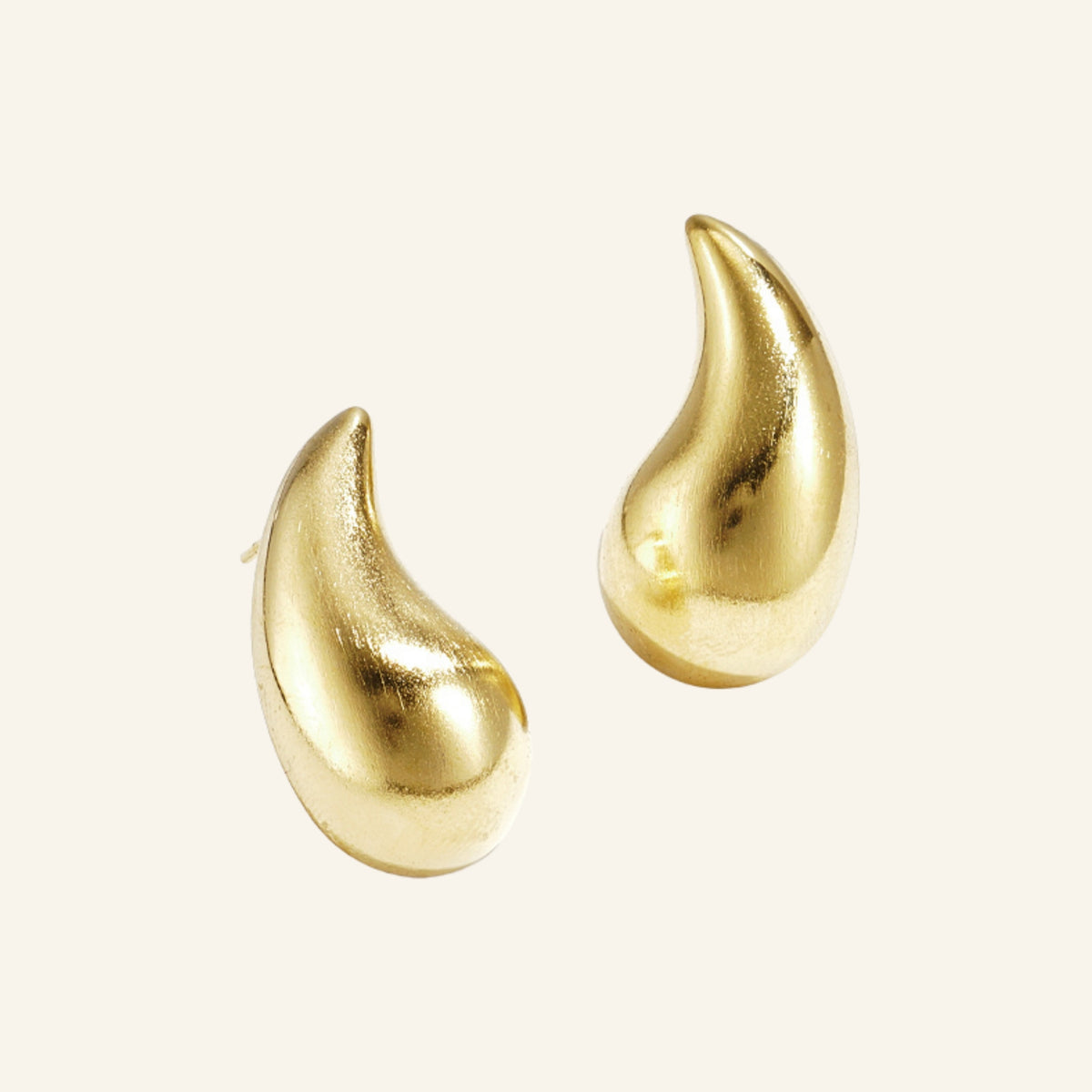 Druppel oorbellen – goud, vrijstaand op beige