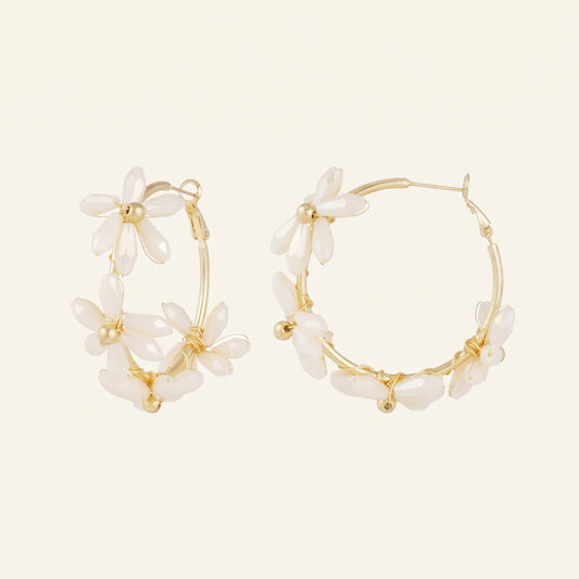 Bloemen oorbellen kralen goud wit – voorkant op beige