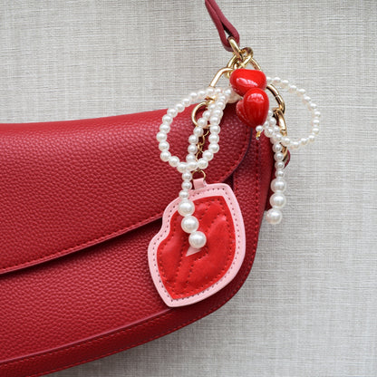 Kus met parels bag charm aan rode tas
