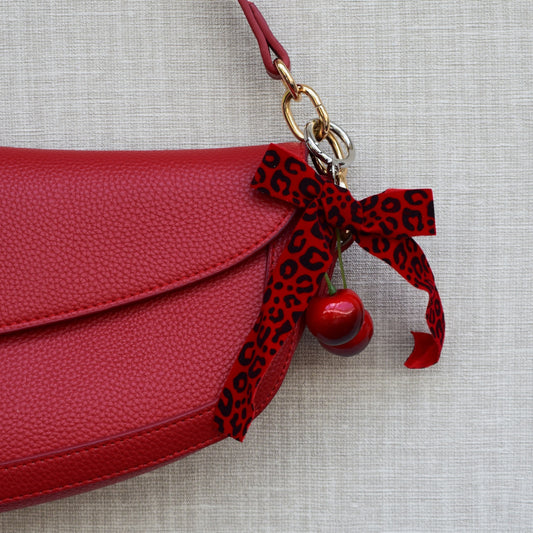 Kersen met panterprint strik bag charm aan rode tas