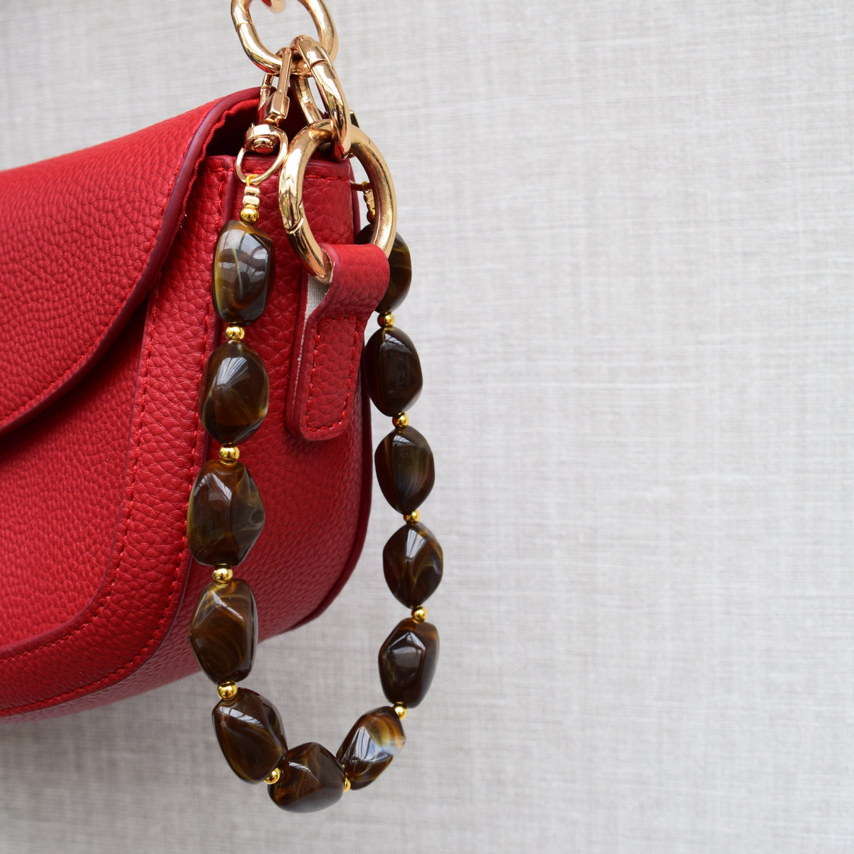 Beaded bag charm brown on a red bag, side view