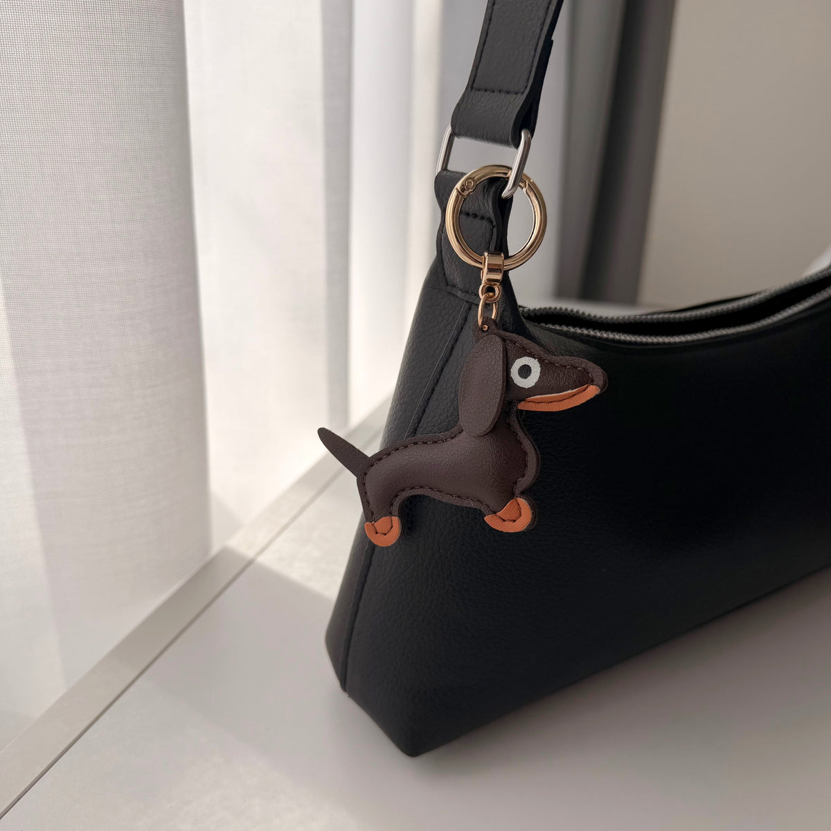 Hond van stof bag charm aan zwarte tas