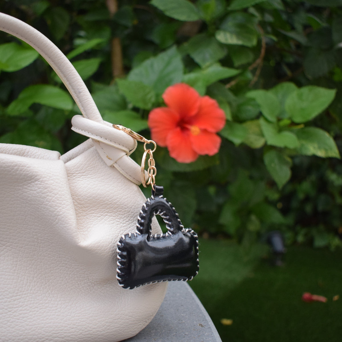 Mini tasje bag charm zwart aan witte tas bij bloemen