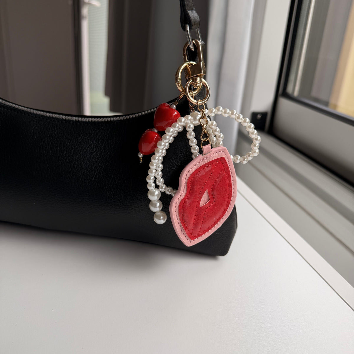 Kus met parels bag charm aan zwarte tas