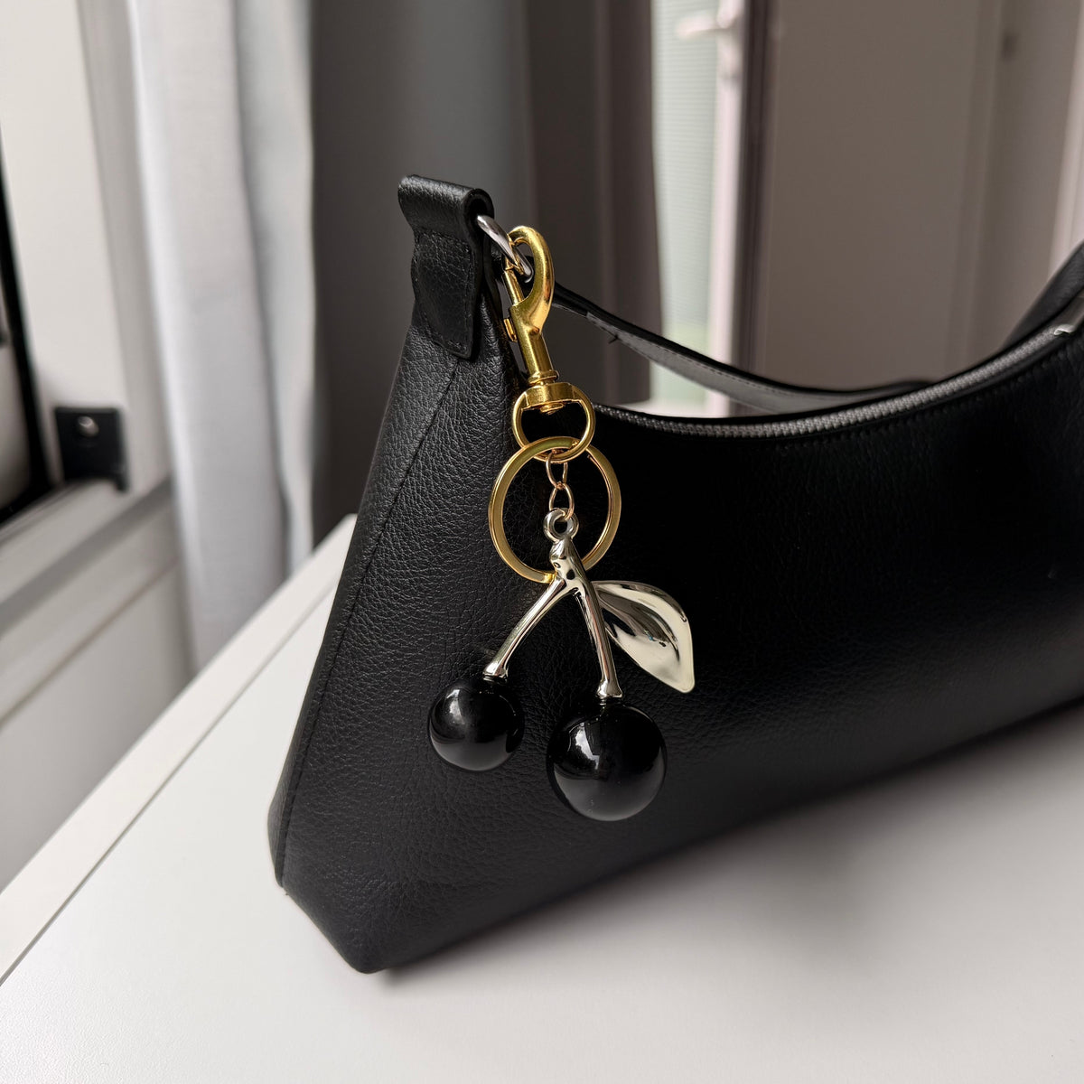 Kersen bag charm zwart aan zwarte tas