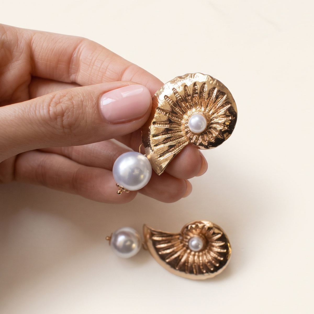 Schelp parel oorbellen goud – vastgehouden in de hand