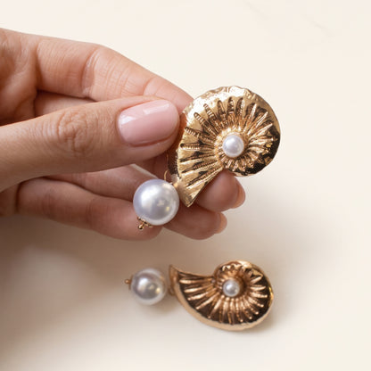 Schelp parel oorbellen goud – vastgehouden in de hand
