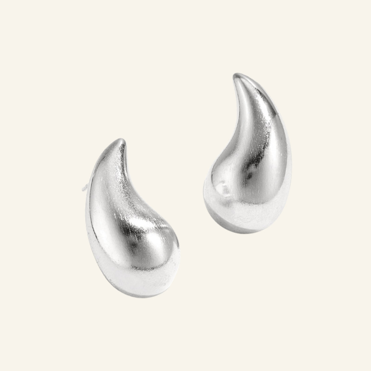 Druppel oorbellen – zilver, vrijstaand op beige