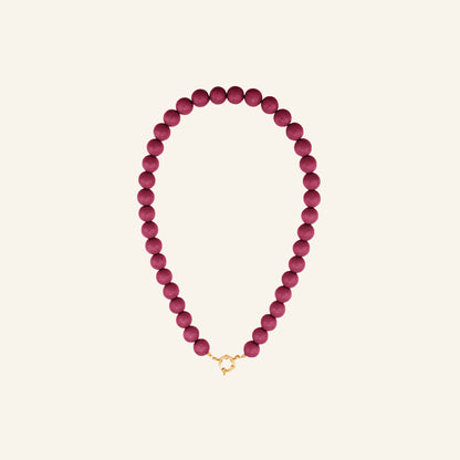 Glanzende kralenketting – fuchsia vrijstaand op beige