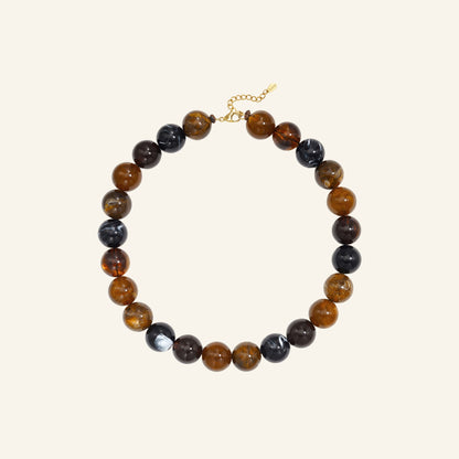 Chunky ronde kralenketting – donkere koffiekleur vrijstaand op beige
