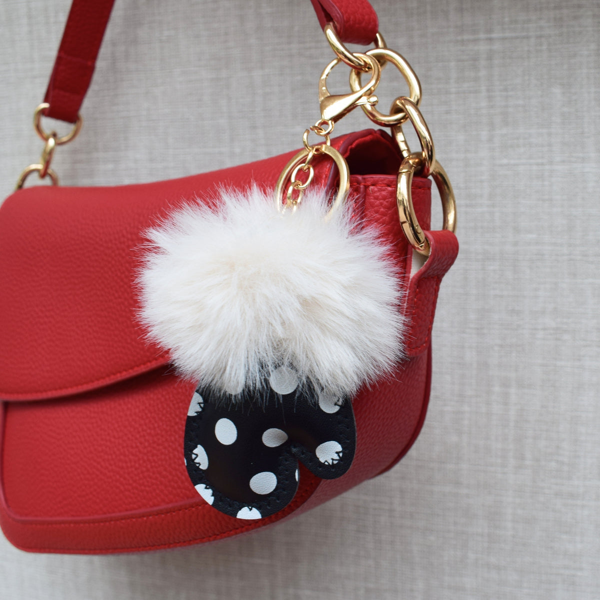 Handschoen polka dots fluffy bag charm aan rode tas