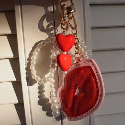Kus met parels bag charm in zonlicht aan zwarte tas