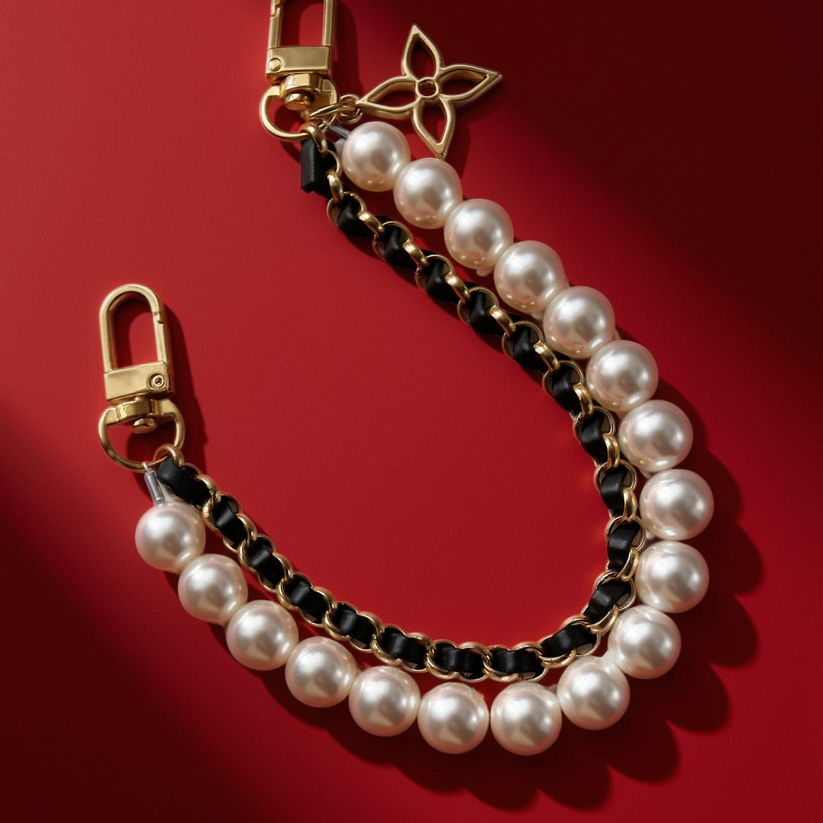 Parels bag charm zwart op rood, close-up