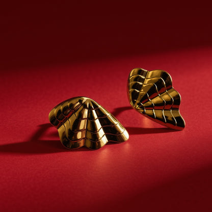 Gold shell earrings – angled view on red