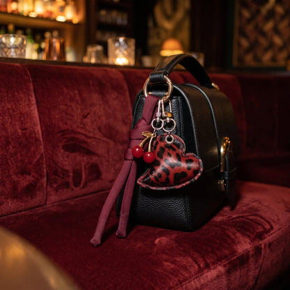 Hart en kers bag charm rood aan een zwarte tas, sfeerfoto