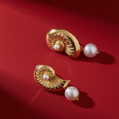 Schelp parel oorbellen goud – op rode achtergrond