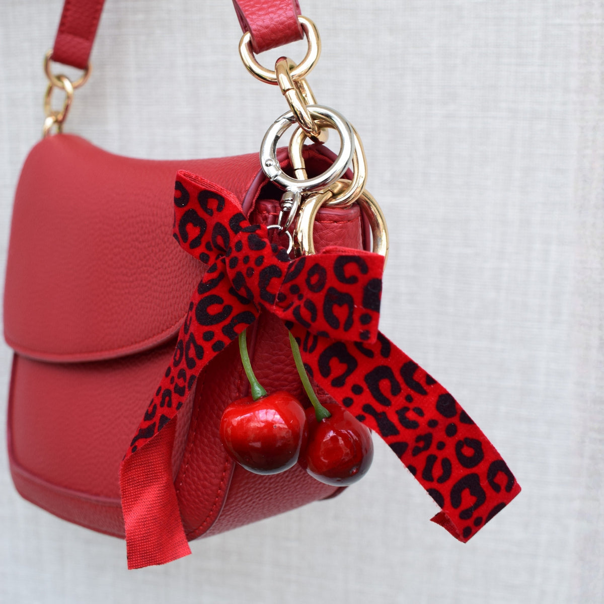 Kersen met panterprint strik bag charm aan rode tas