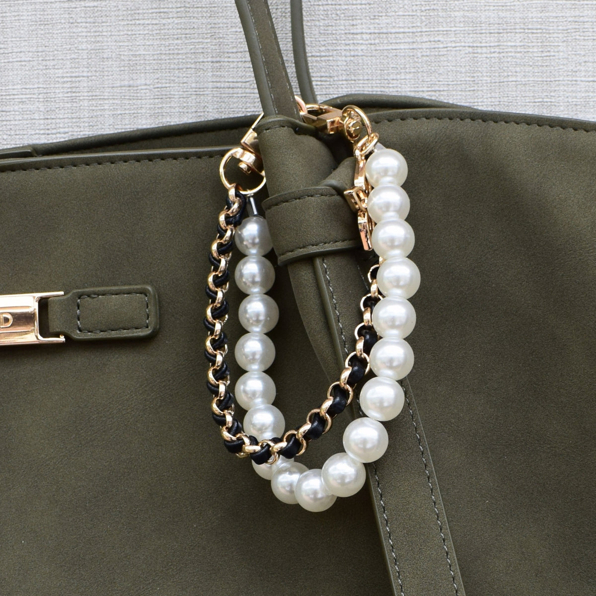 Parels bag charm zwart aan groene tas, close-up