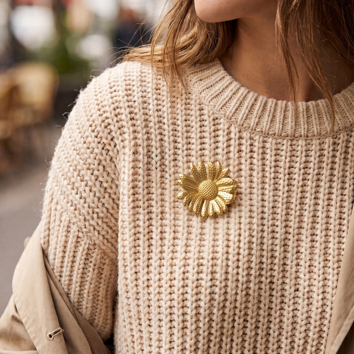 Bloem broche goud op een beige gebreide trui