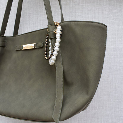 Parels bag charm zwart gedragen aan groene tas