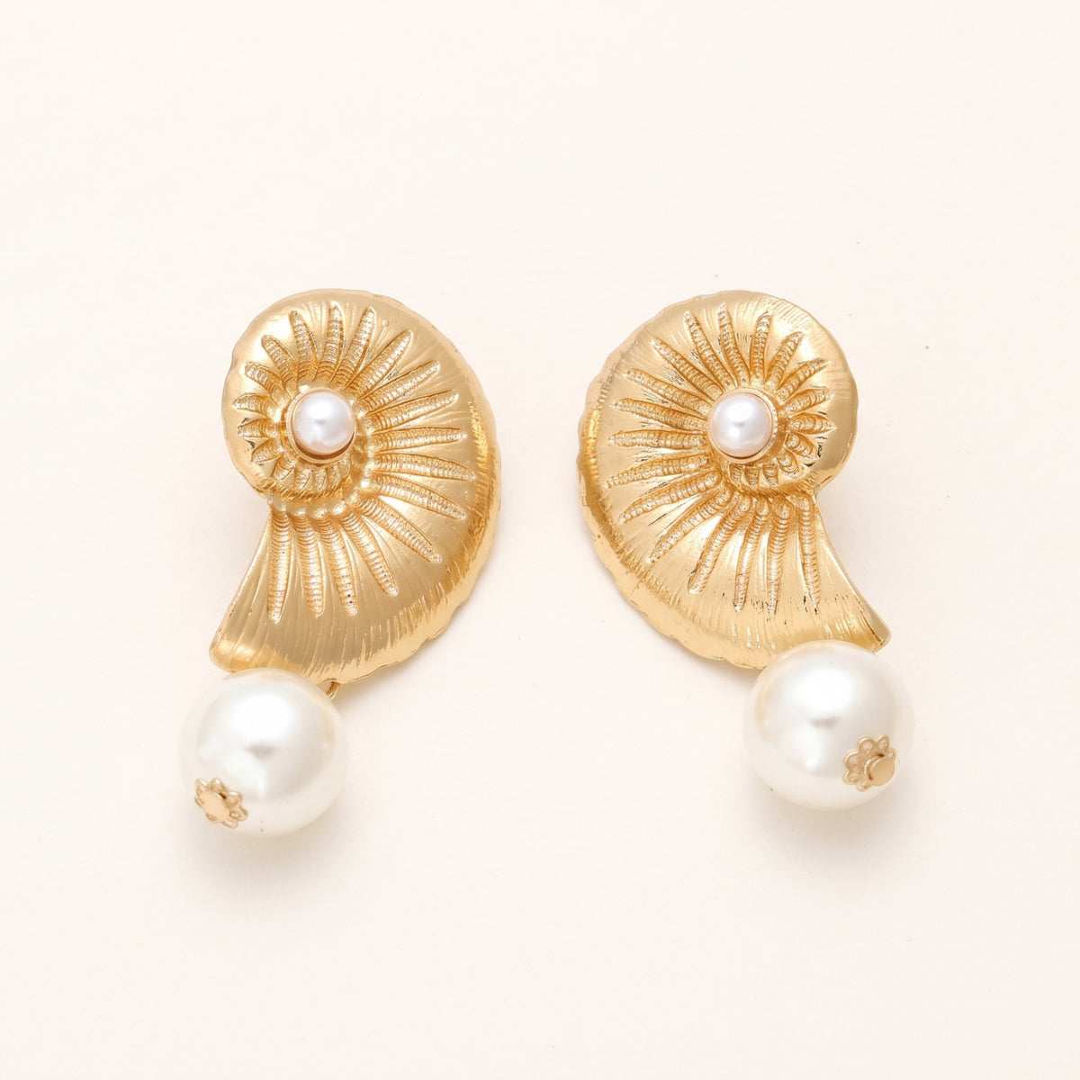 Schelp parel oorbellen goud – detail op lichte achtergrond