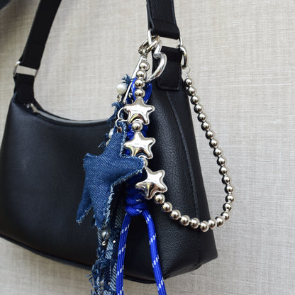 Ster van stof bag charm blauw aan zwarte tas