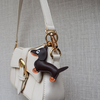 Hond van stof bag charm aan witte tas