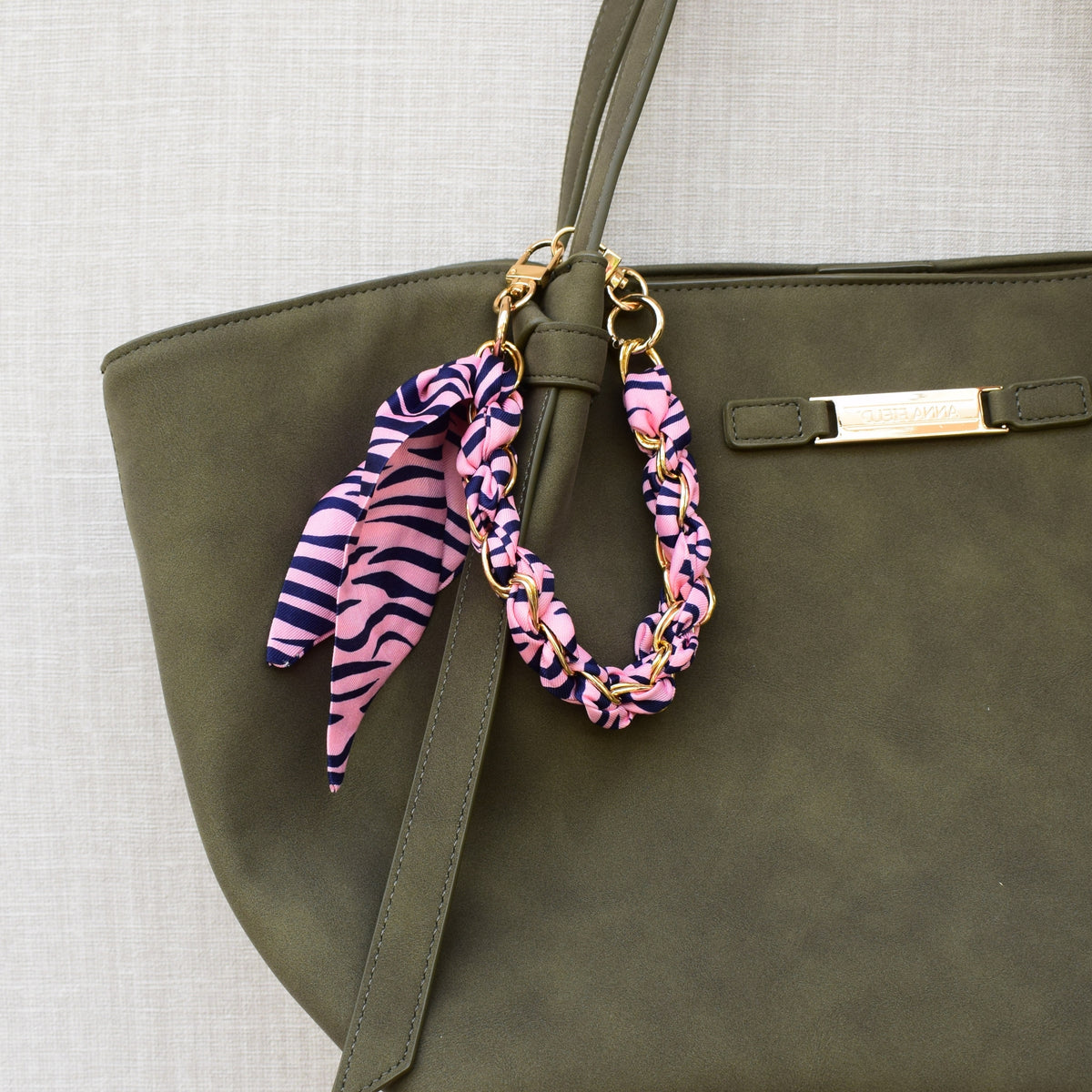 Sjaal bag charm roze aan groene tas, close-up