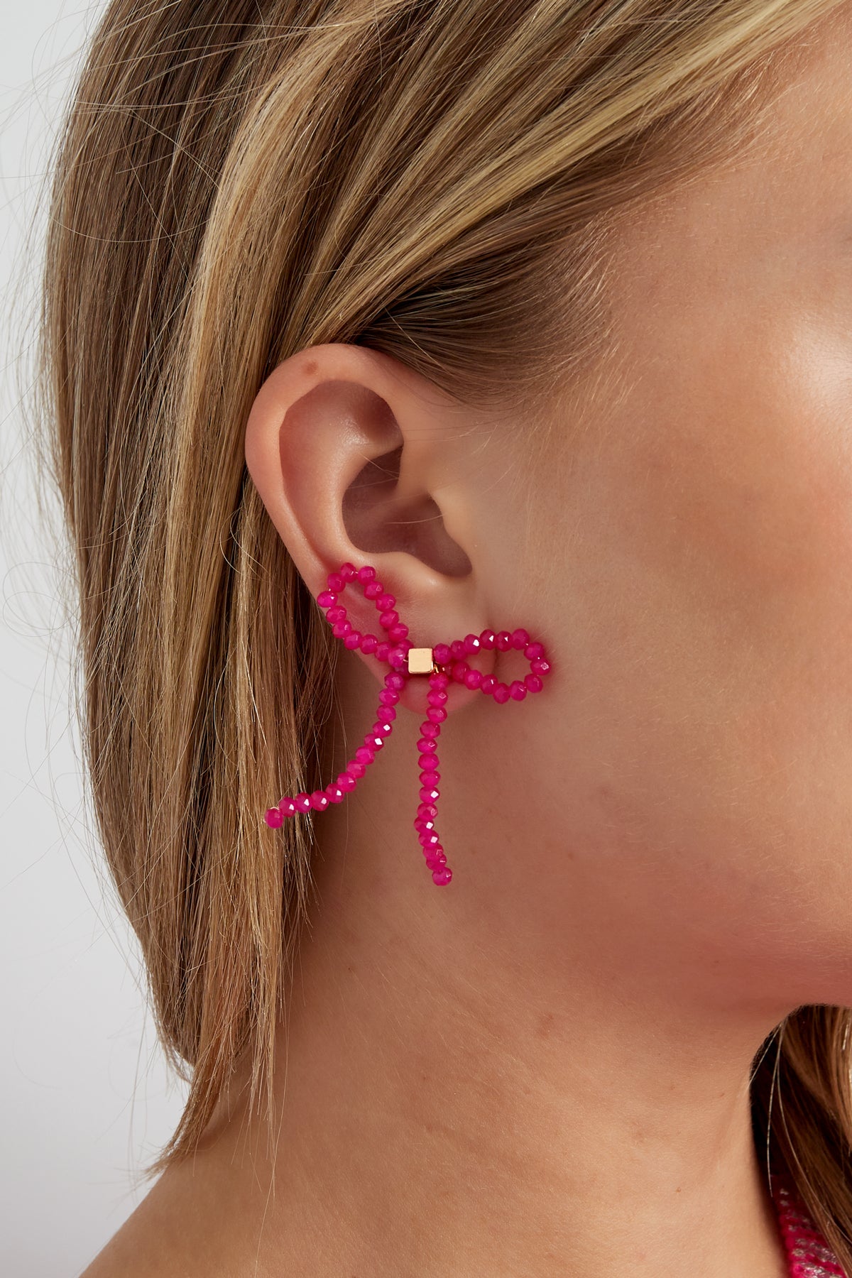 Strik oorbellen strass – roze, gedragen aan het oor